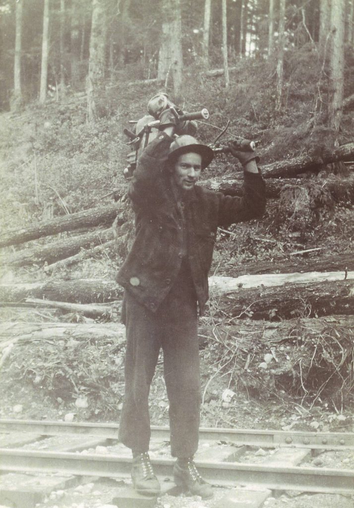 Walter Hogg on the job with a heavy chainsaw on his shoulder.